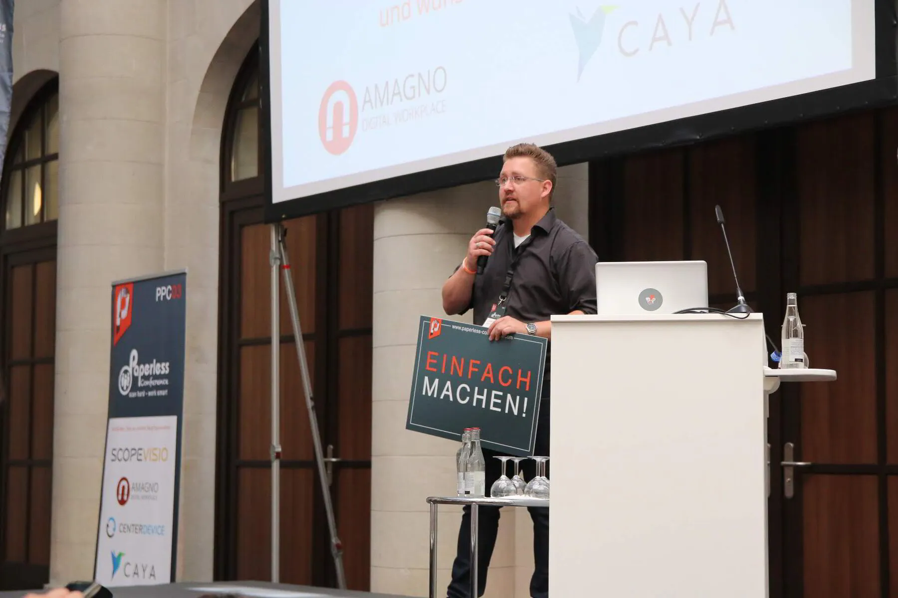 André Nünninghoff am Rednerpult der Paperless Conference mit Einfach-machen-Schild